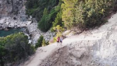 Seyahat ve açık hava macera konsepti. Dağın kenarında yürüyüş yapan bir çift. İnsanlar yaz tatillerinde doğanın tadını çıkarırlar. Sırt çantalı bir çift yürüyüşçü dağlarda panoramik manzaranın keyfini çıkarıyor.,