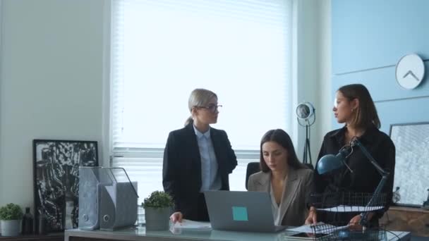 女性はビジネスで新しいプロジェクトを議論しており 彼らはオフィスにいます 3人の若い女の子がオフィスで仕事の話をしてる書類を調べてる — ストック動画