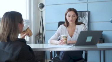 Ofiste çalışırken iletişim kuran iki iş kadını. İki kendine güvenen ofis çalışanı kadın konuşuyor ve laptopa bakıyor.. 