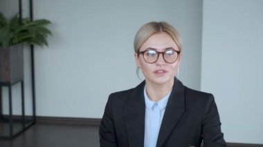 Kendinden emin genç bir kadın evdeki koltukta kameraya konuşuyor. Güzel yüz sevinç ve mutluluk dolu bir başarıyla sarmalanır..