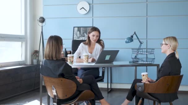 3人の同僚がコミュニケーションを取り プレゼンテーションを行います 3人のビジネスの女の子がテーブルでコーヒーを飲みながら椅子に座って新しいプロジェクトについて話し合っています — ストック動画