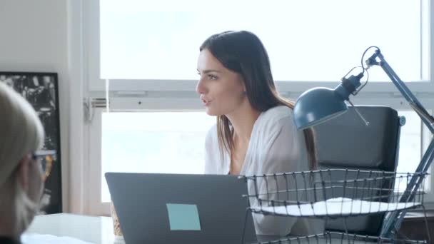 ビジネスの女性は彼女の机に坐るとき同僚と通信する — ストック動画