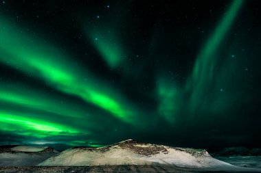 Yeşil Aurora borealis flamaları, Kuzey İzlanda Myvatn Gölü kıyılarında karla kaplı psuedo kraterleri.