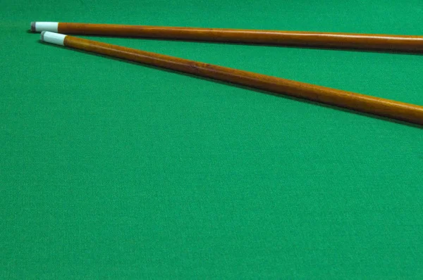 billiard cues / two pool cues on the green background of the pool table