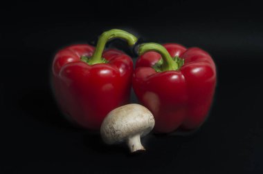 Siyah arkaplanda kırmızı biber ve mantar izole edilmiş.