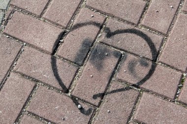 Parktaki fayanslı zeminde siyah boyanmış kalp.