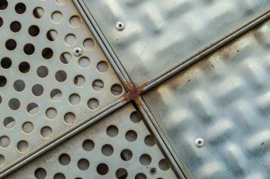 Eski ve paslı çapraz metal ızgara ve delinmiş daire sanatı.