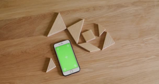 Telefone inteligente em madeira de mesa de madeira com tangrama de madeira — Vídeo de Stock