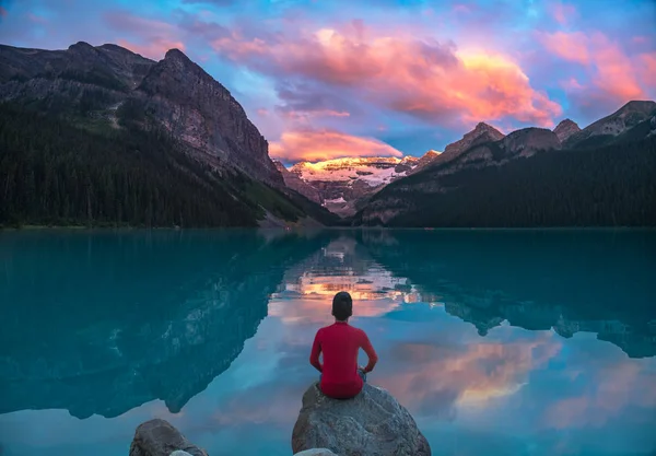 Man zitten op rots kijken naar Lake Louise ochtend wolken met reflecties — Stockfoto