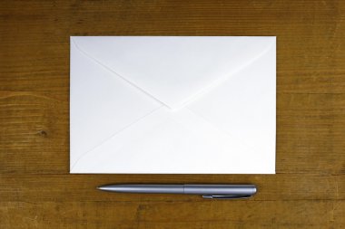 Beyaz zarf ve ahşap zemin üzerine kalem