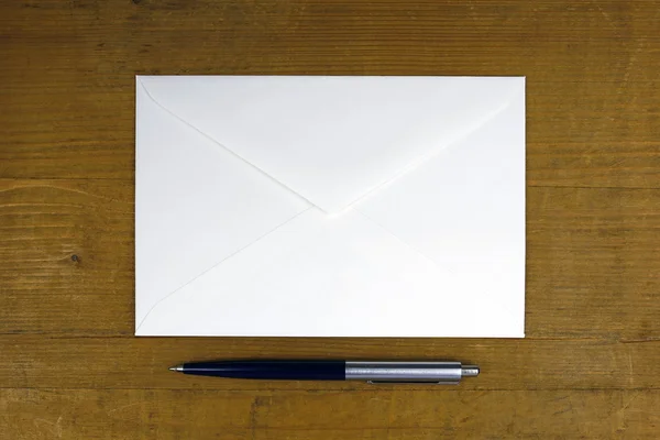 Білий конверт з ручкою на дерев'яному фоні — стокове фото