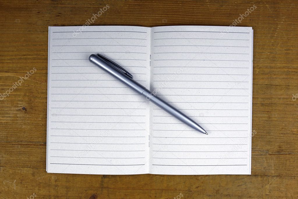 pen on open notebook on wooden background