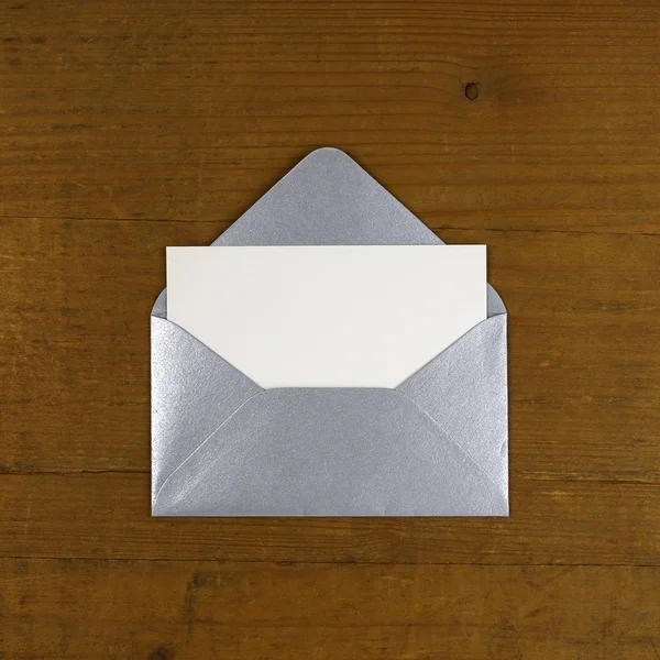木製の背景に銀の封筒を開く — ストック写真