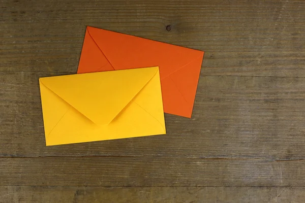 Yellow and orange envelopes on wooden background, copy space on the side — Stock Photo, Image