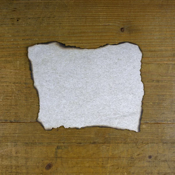 Burnt paper on wooden background — Stock Photo, Image