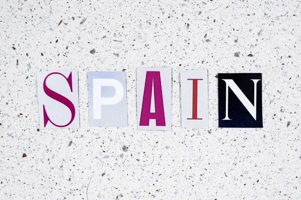 Spain word cut from newspaper on handmade paper texture — Φωτογραφία Αρχείου