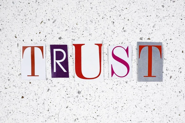 Trust word cut from newspaper on handmade paper texture — Stock Photo, Image