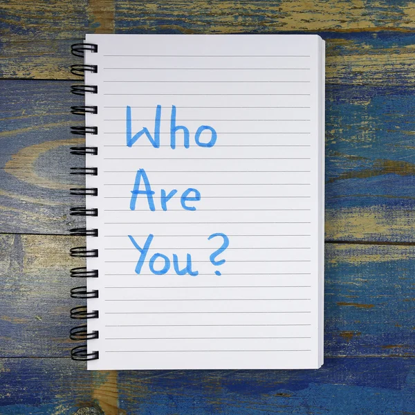 Who Are You? text written in notebook on wooden background