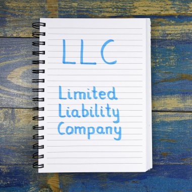 Ahşap arka plan üzerinde defterde yazılı Limited Şirket Llc - kısaltma