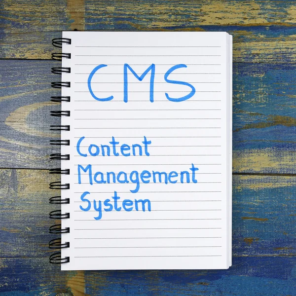 CMS- Content Management System acronym written in notebook on wooden background