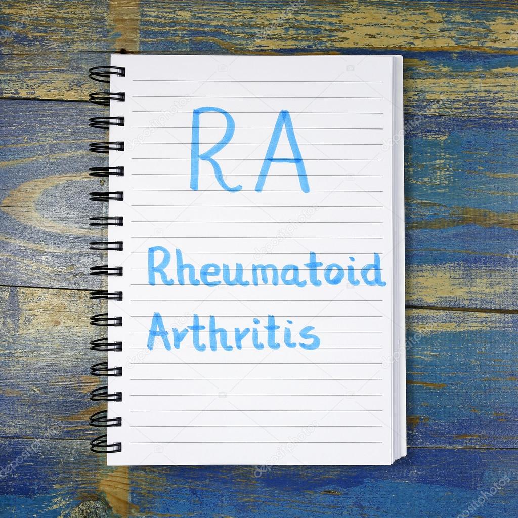 RA- Rheumatoid Arthritis acronym written in notebook on wooden background