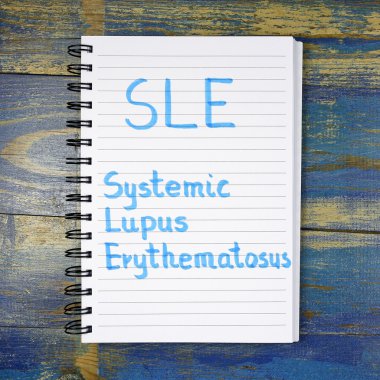 Ahşap arka plan üzerinde defterde yazılı Sle - Sistemik Lupus Erythematosus kısaltma