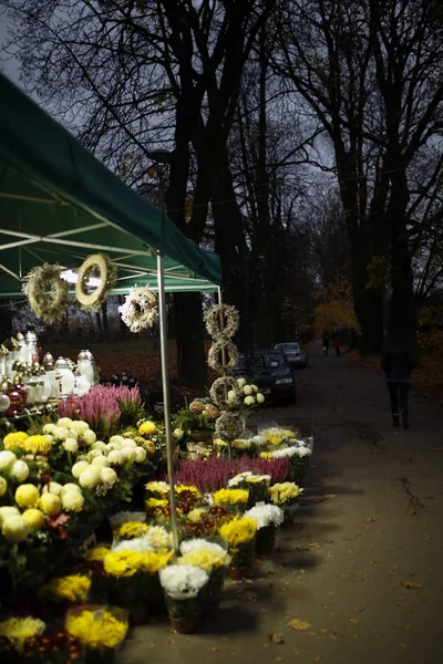 Stå med ljus och krysantemum bredvid kyrkogården på alla helgons dag — Stockfoto