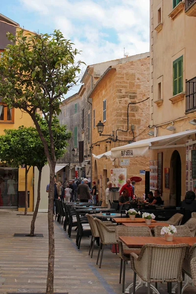 ALCUDIA, MAJORCA, ESPAÑA, 4 DE ABRIL DE 2016: Restaurante al aire libre en una de las encantadoras calles de Alcudia. Es un destino turístico muy popular en Mallorca, conocido por el carácter muy bien conservado de una ciudad histórica . — Foto de Stock