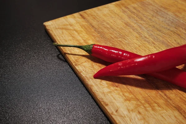 Chiles rojos sobre tabla de cortar de madera — Foto de Stock