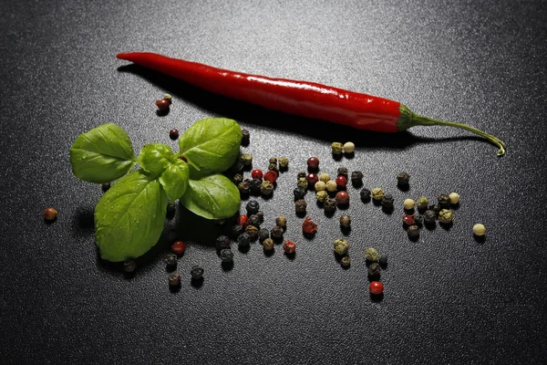 Chili pepper, basil and colorful pepper on black background — Stock Photo, Image
