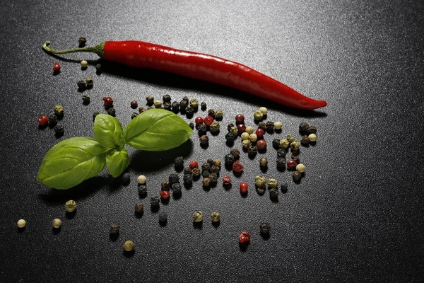 Red chili pepper and basil leaves on black background — Stock Photo, Image