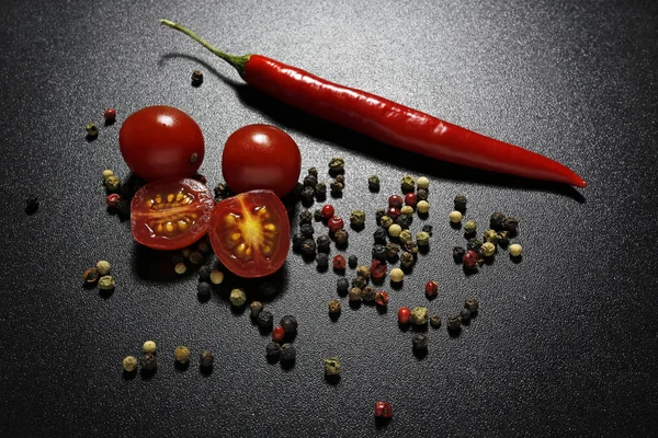 Red chili pepper and cherry tomatoes on black background — Stock Photo, Image