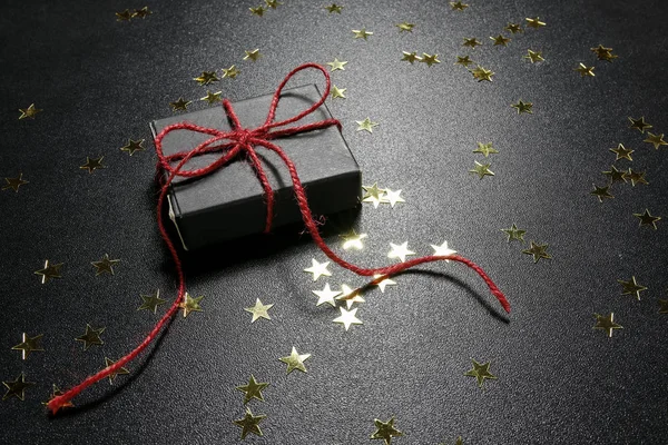 Presente de Natal com estrelas douradas brilhantes em um fundo preto — Fotografia de Stock