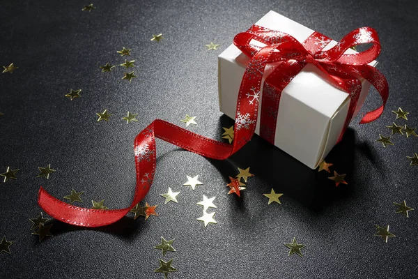 Presente de Natal com estrelas de ouro brilhantes no fundo preto — Fotografia de Stock
