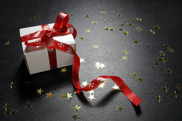Рождественский подарок с сияющими золотыми звездами на черном фоне — стоковое фото