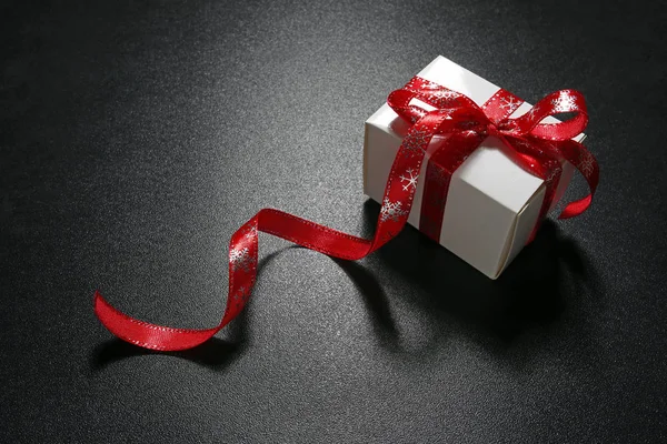 Χριστουγεννιάτικο δώρο με κόκκινη κορδέλα σε μαύρο φόντο — Φωτογραφία Αρχείου