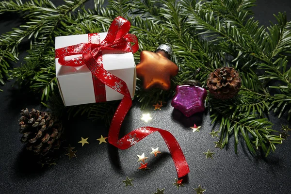 Christmas present with baubles, cones and fir tree on black background — Stock Photo, Image