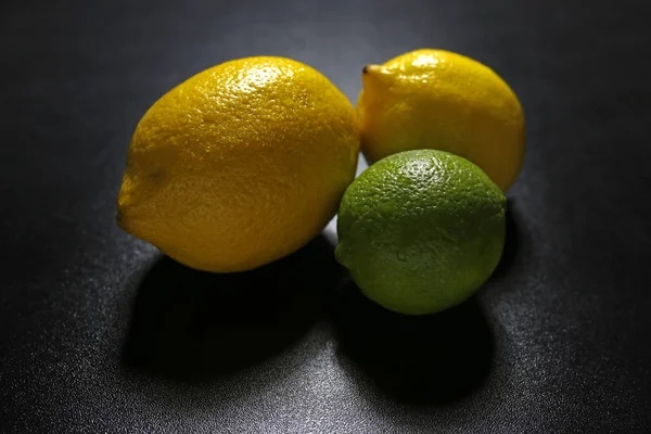 Limoni e frutti di lime su sfondo nero — Foto Stock