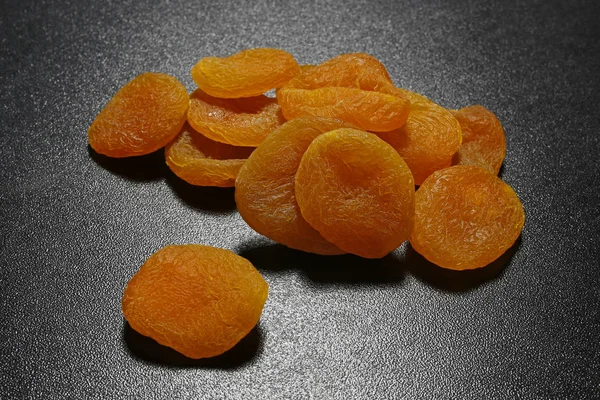 Torkade aprikoser på svart glänsande bakgrund — Stockfoto