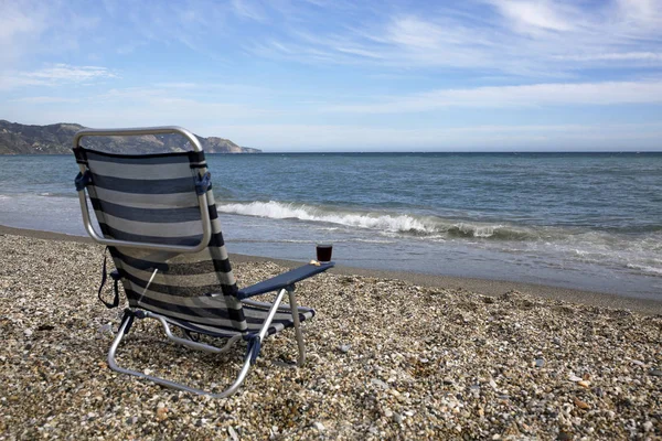 Cama de sol vazia com copo de vinho tinto na praia — Fotografia de Stock