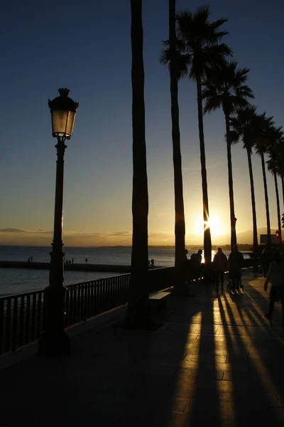 Bulevar costero en Marbella, España con rayos de sol al atardecer —  Fotos de Stock