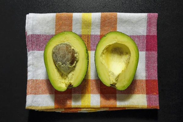 Halved avocado on kitchen cloth — Stock Photo, Image