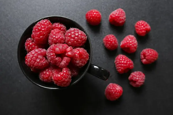 Fresh raspberries in a black cup — Stock Photo, Image