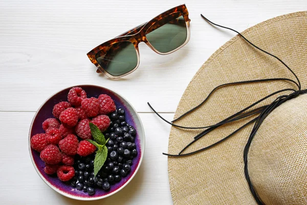 Beyaz ahşap zemin üzerinde sunglassses, hasır şapka ve yaz taze meyve