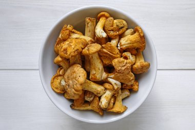 Beyaz ahşap zemin üzerinde bir kapta taze hasat Cantharellus cibarius mantar