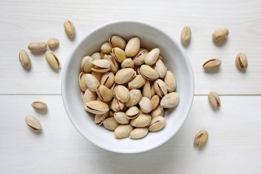 Beyaz ahşap zemin üzerine bir kase fıstık fındık
