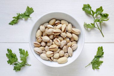 Beyaz ahşap zemin üzerine bir kase fıstık fındık