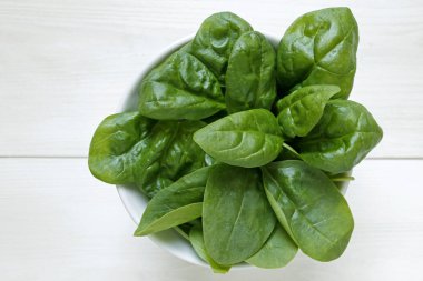 Beyaz ahşap arka plan üzerinde taze bebek ıspanak yaprakları