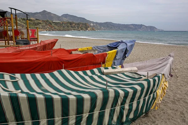 vintage fishing boats covered with colorful fabric on empty beach