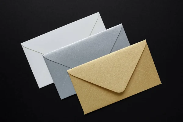 Branco, ouro, envelopes de prata sobre fundo preto — Fotografia de Stock